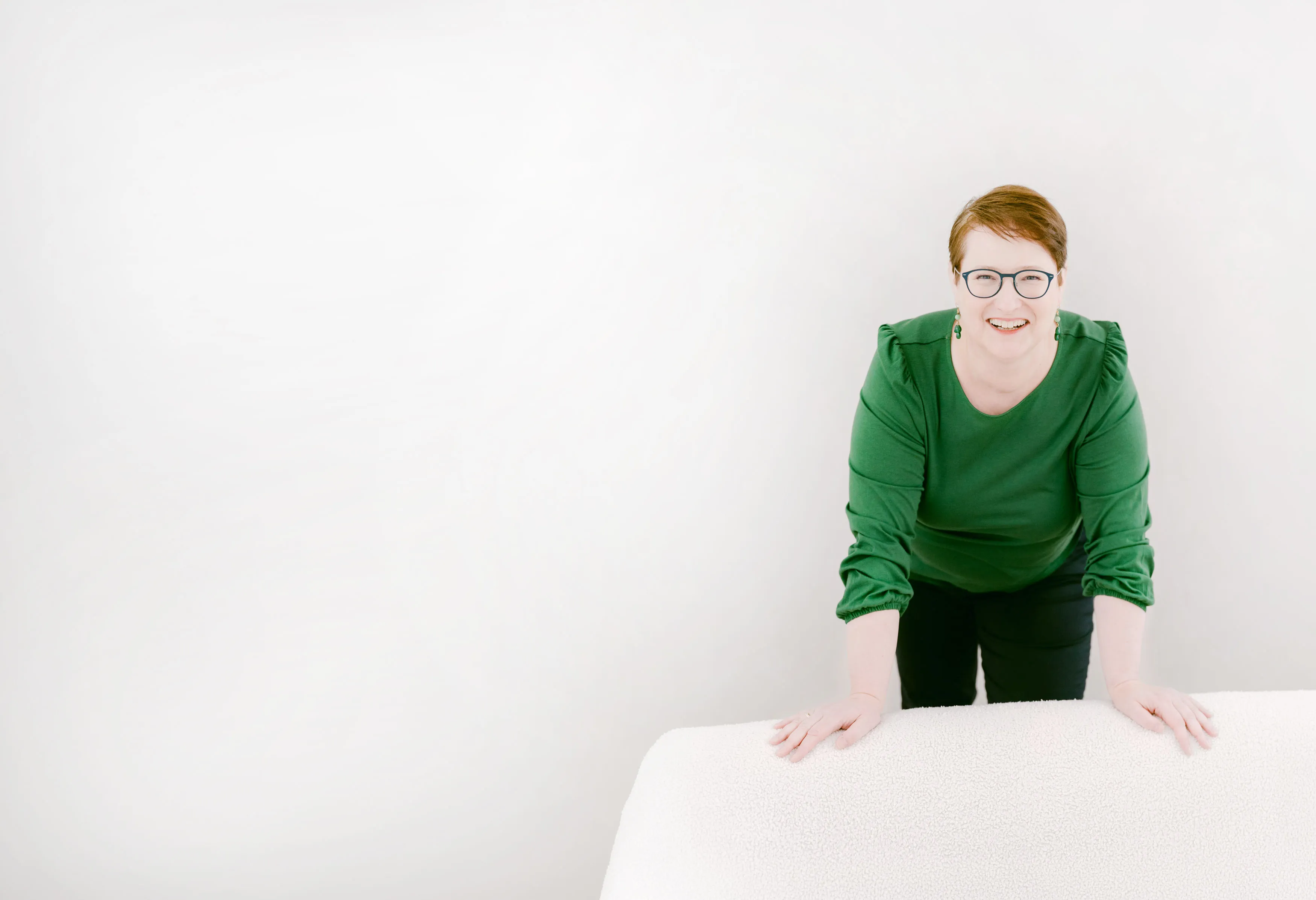 Dr. Ute Heeger in grüner Bluse, lächelnd auf einen Tisch gestützt